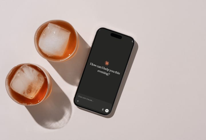 A top-down image a mobile phone showing the Claude launch scree next to two drinks with square ice cubes in them.